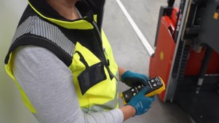 Mitarbeiterin bedient explosionsgeschützten Hochhubwagen L03 EX von Linde Material Handling per Fernbedienung.