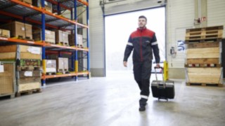 Les techniciens Fenwick - au service de votre chariot élévateur Un technicien Fenwick-Linde marche dans un entrepôt
