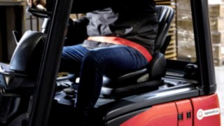 Il conducente di un muletto utilizza la cintura di sicurezza Linde OrangeBelt™ per una maggiore sicurezza di esercizio