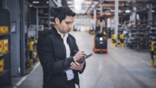 Un collaborateur de Linde se trouve dans l’entrepôt et prend des notes sur sa tablette.