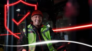 Persona con indumenti da lavoro e casco di protezione, seduta in un carrello elevatore Linde