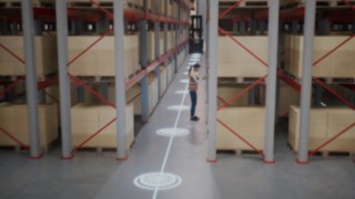 Animazione di un dipendente con gilet protettivo nel magazzino a corsie strette e delle zone di sicurezza per il riconoscimento delle persone