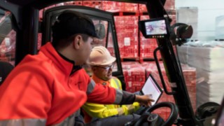 Sicherheitsexperte von Linde MH zeigt einem Staplerfahrer Daten auf einem Tablet. Sicherheitsexperte von Linde MH zeigt einem Staplerfahrer Daten auf einem Tablet.