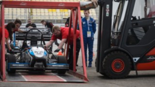 Un carrello elevatore a noleggio di Linde solleva una macchina da corsa con un dispositivo speciale