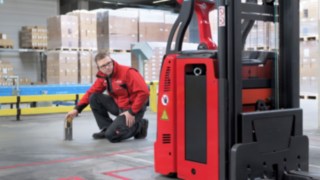 Un employé de Linde est agenouillé devant un L-MATIC et vérifie que tout est en ordre.