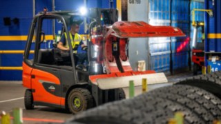 Mitarbeiter von Michelin Tyre PLC greift mit einer Reifenklammer am Linde E20 nach einem Reifenstapel.